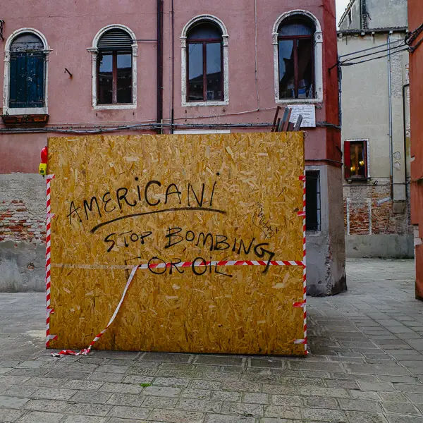 An 'Americani, stop bombing for oil' graffito decorates a temporary structure in Venice, Italy.